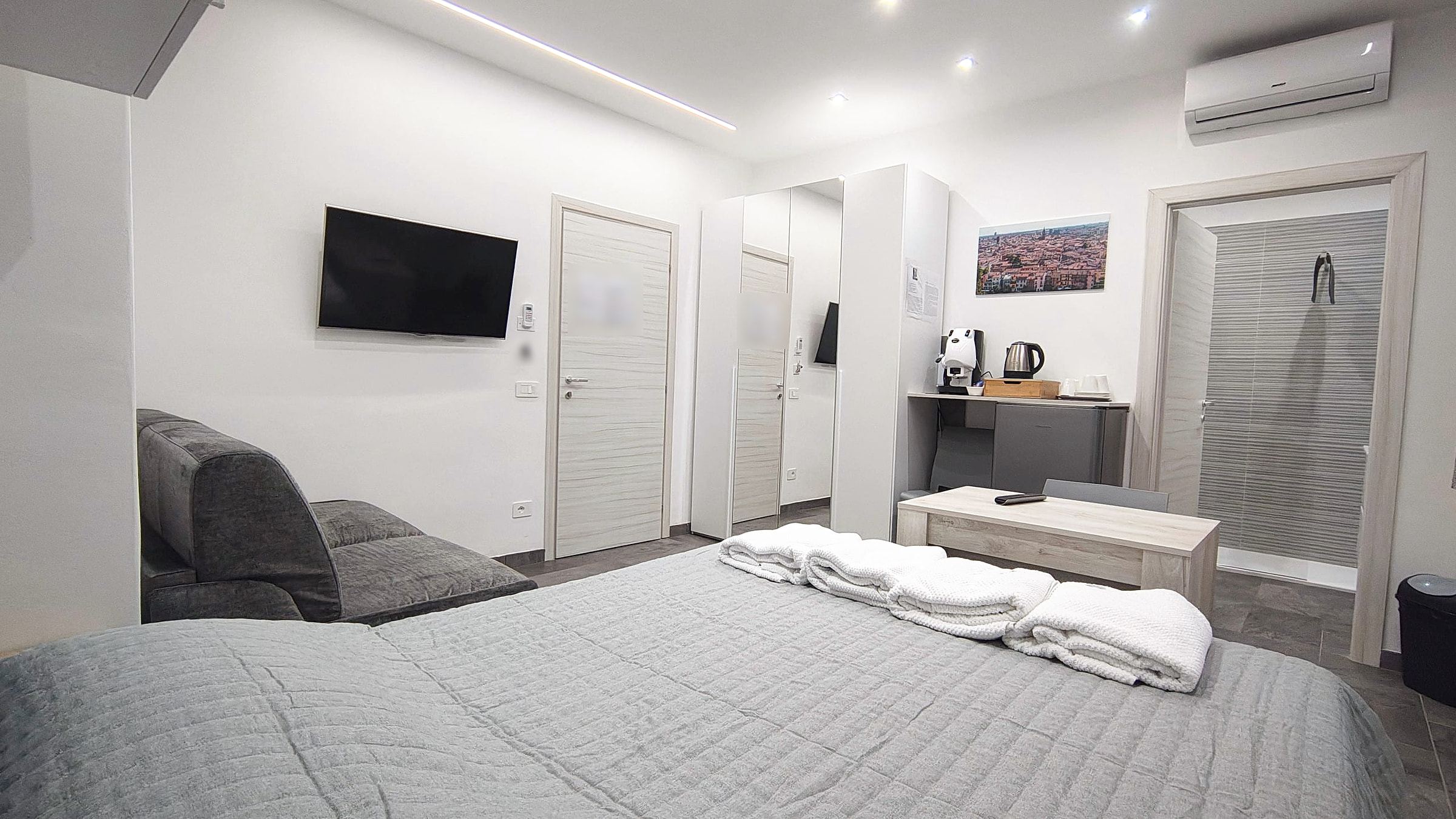 Camera quadrupla con letto, armadio a specchio, angolo caffè e varco sul bagno con doccia walk-in