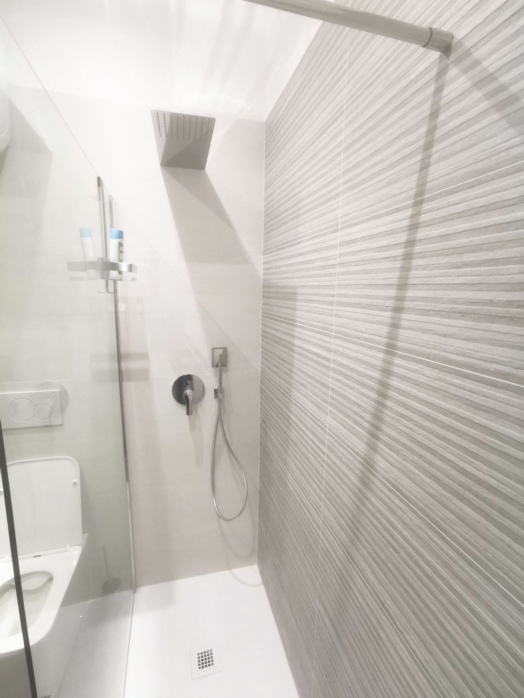 Doccia walk-in luminosa con vetro trasparente e parete di piastrelle chiare