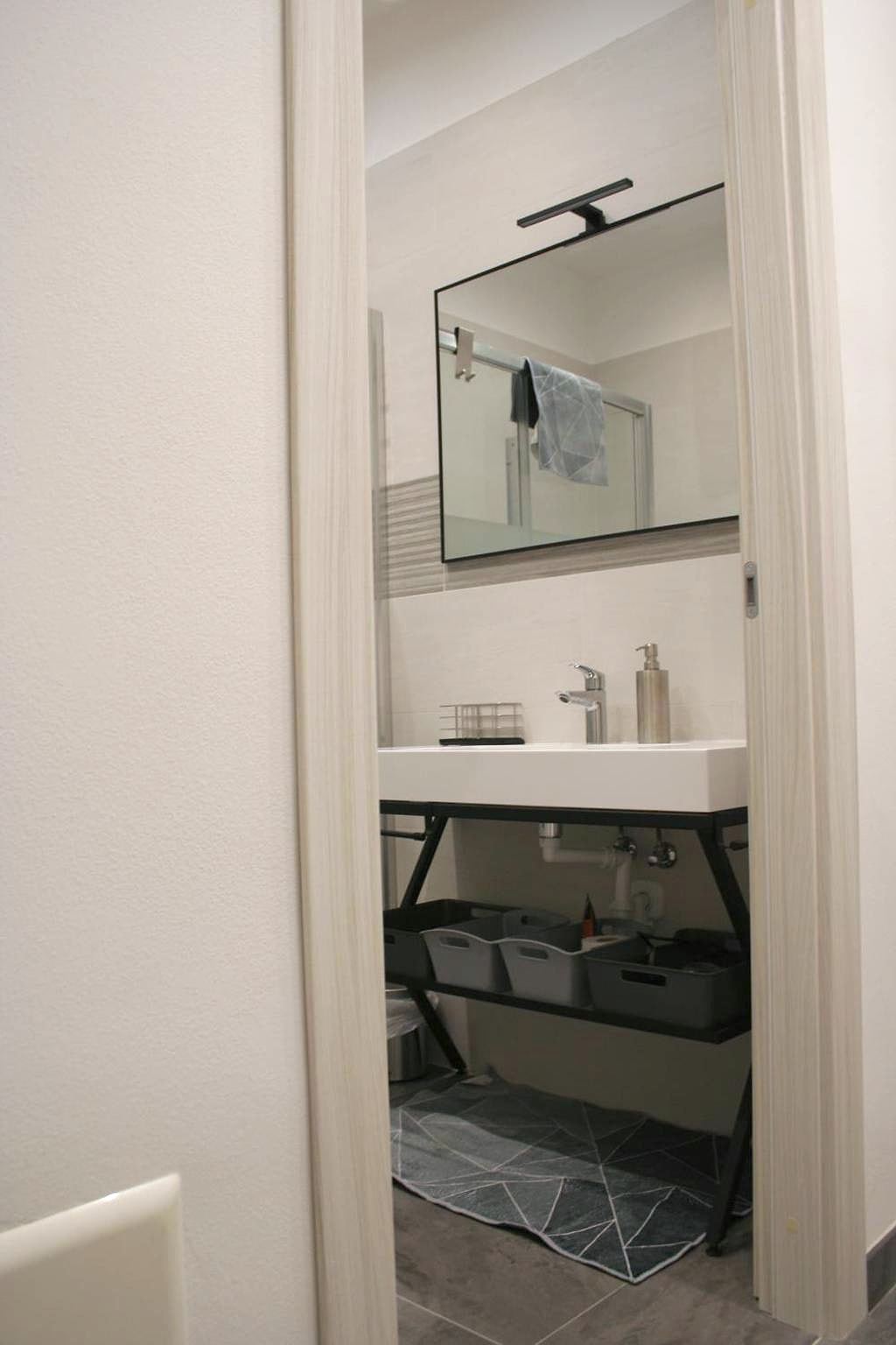 White basin on a black metal frame with mirror in the studio bathroom
