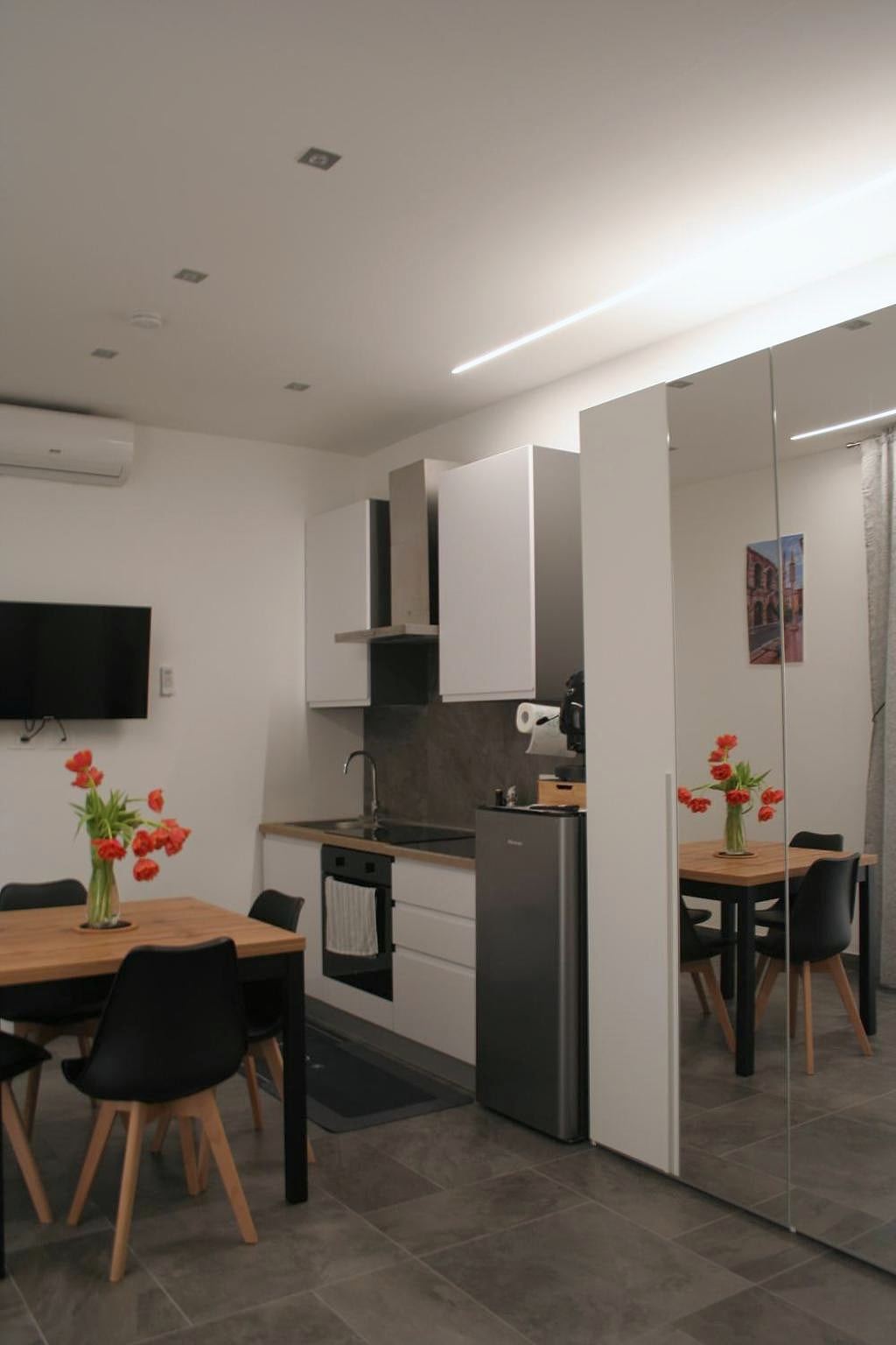White kitchen with fridge, table with black chairs and TV in the studio