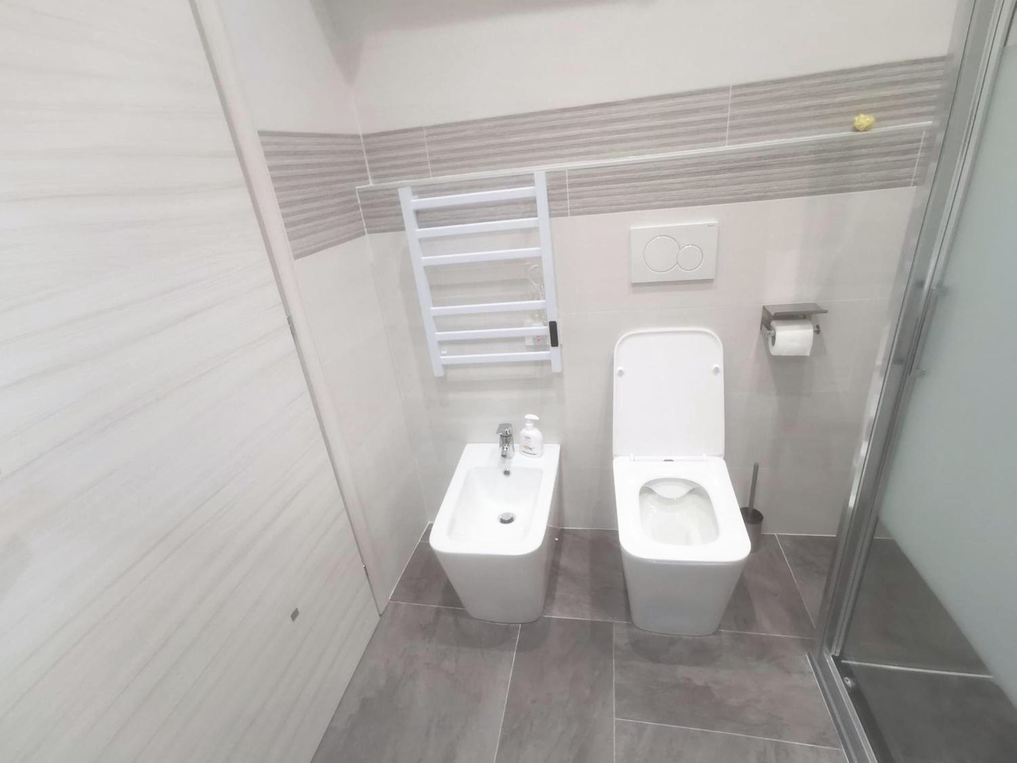 Studio bathroom with toilet, bidet, shower with frosted glass and heated towel rail