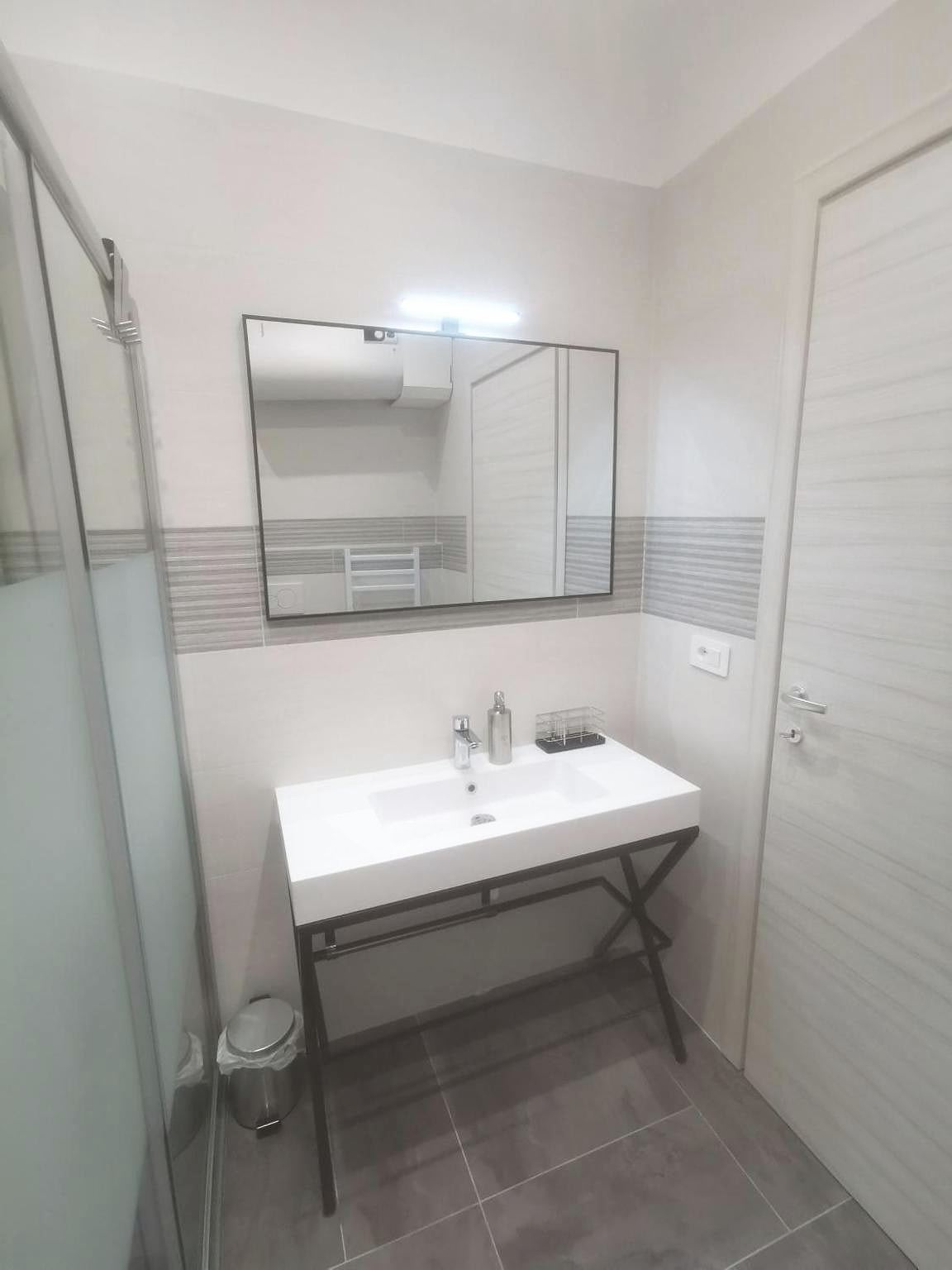 Basin on a black metal frame and mirror in the studio bathroom