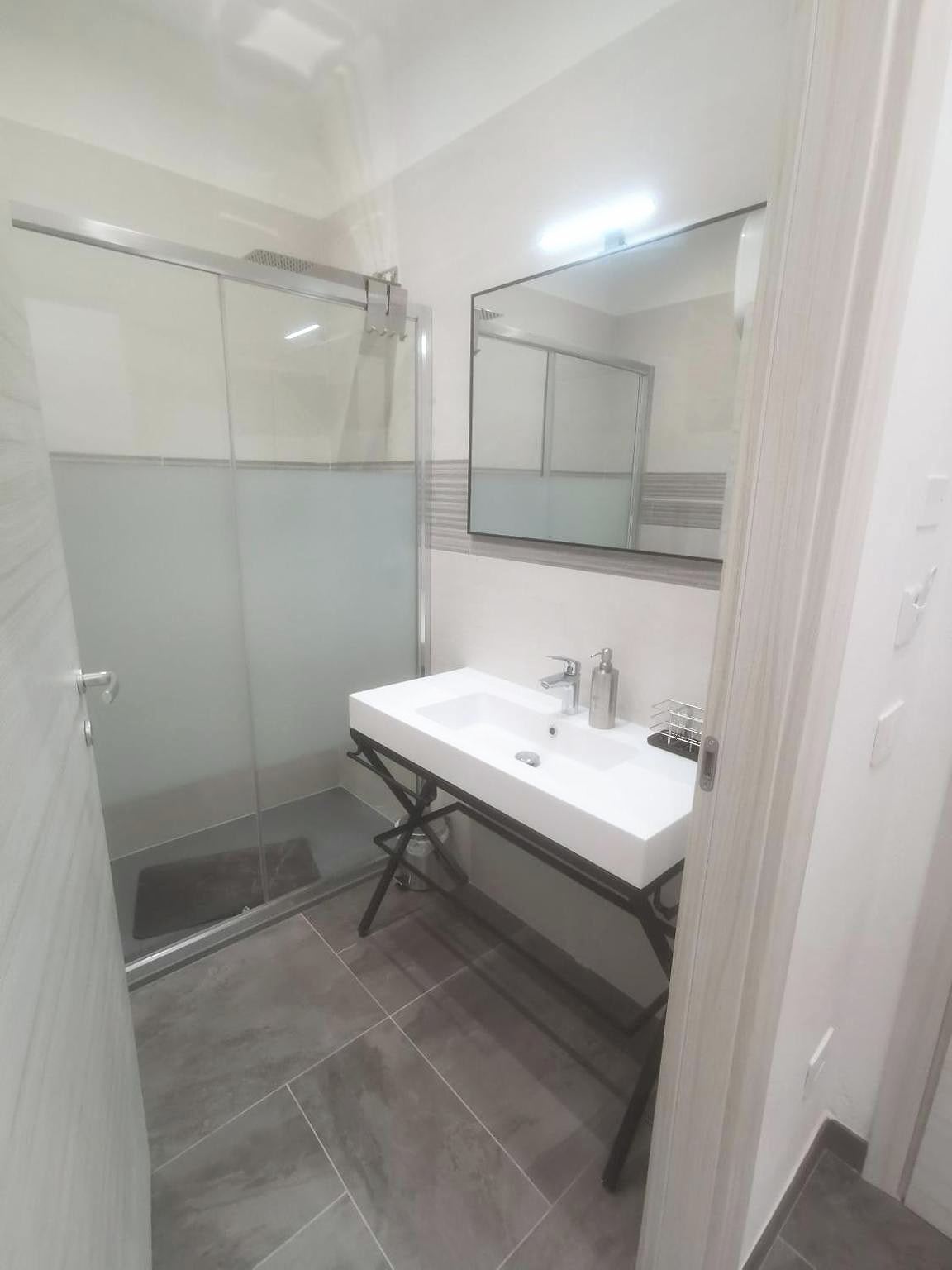 Studio bathroom with frosted-glass shower and white basin with LED-lit mirror